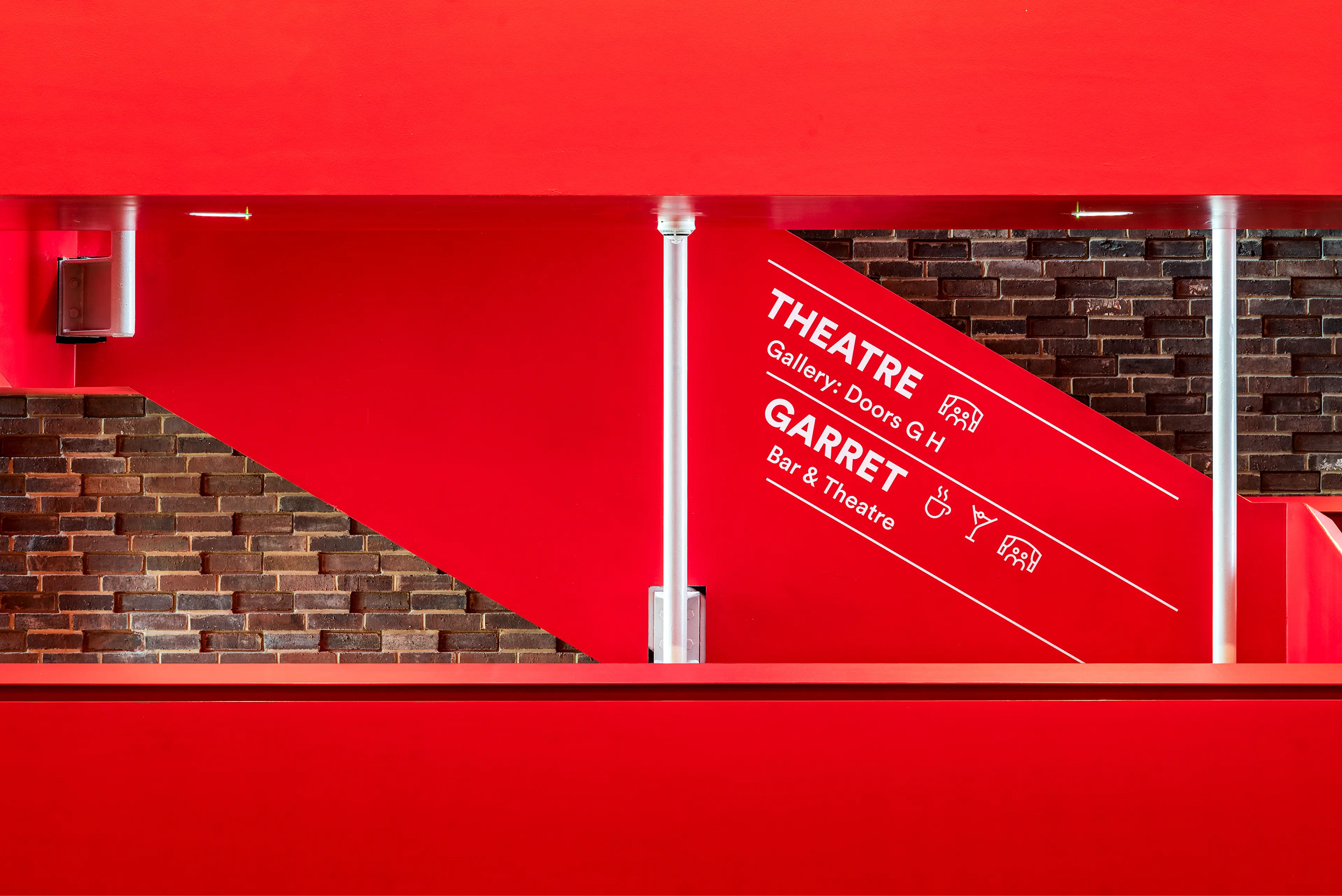 Way finding signage on red staircase from Storyhouse Chester