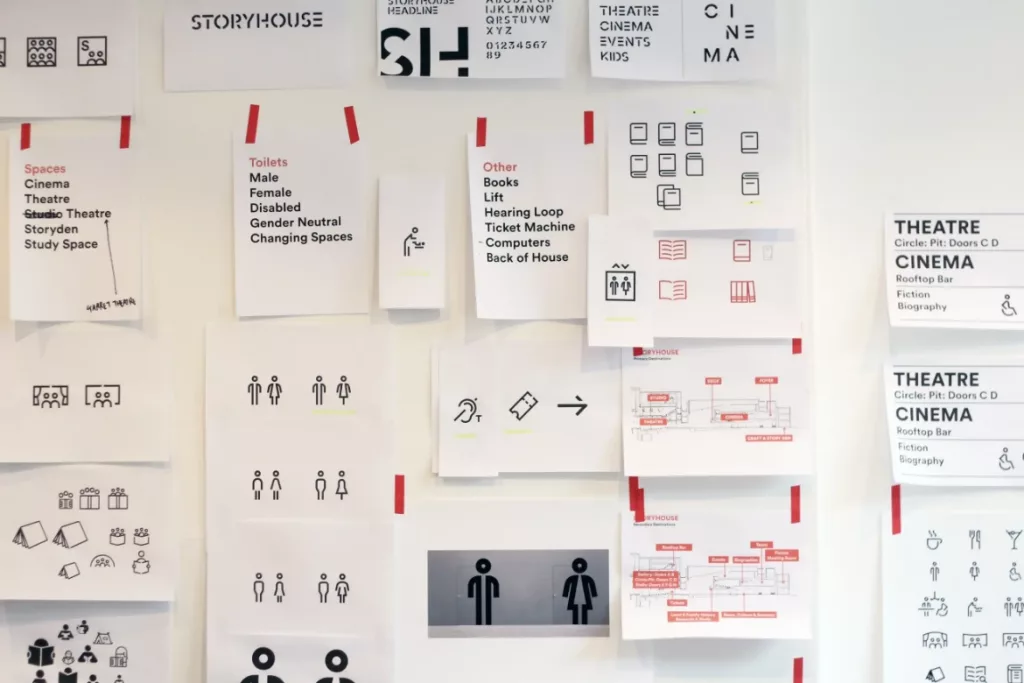 Pinned mockups of signage, icons and wayfinding layouts for a theatre/cinema on a white wall.