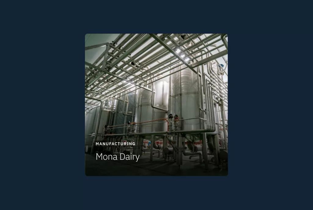 Stainless steel dairy processing tanks and overhead pipes in a manufacturing plant, with visible text Mona Dairy.