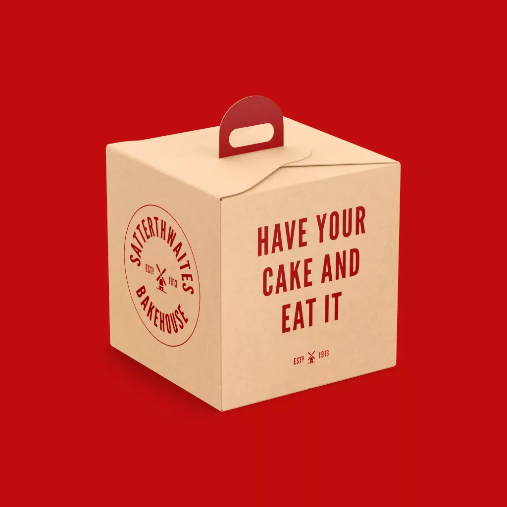Cardboard bakery cake box with a red handle and bold red lettering "Have your cake and eat it," set against a solid red background.