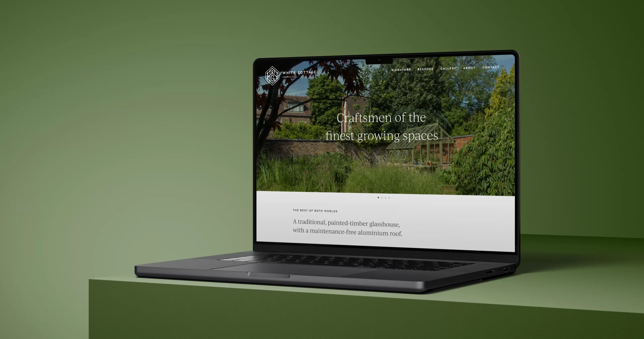 Dark laptop on a green plinth displaying a website with a garden greenhouse photo and headline about craftsmen.