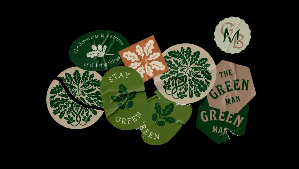 Torn green and beige stickers on black showing stylised Green Man faces, oak leaves and 'Stay Green' text.