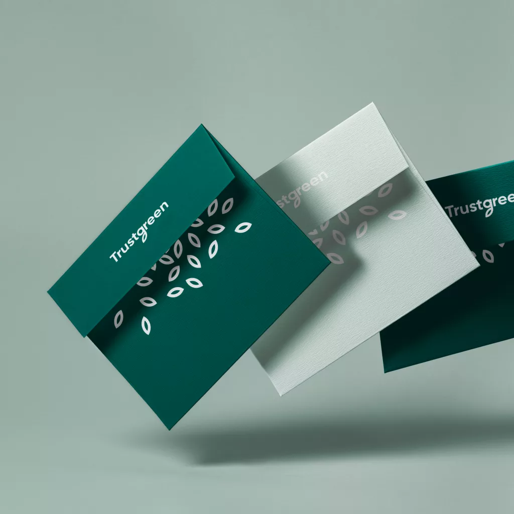Three floating dark and light green business cards with a white leaf pattern and Trustgreen logo on a pale sage background.