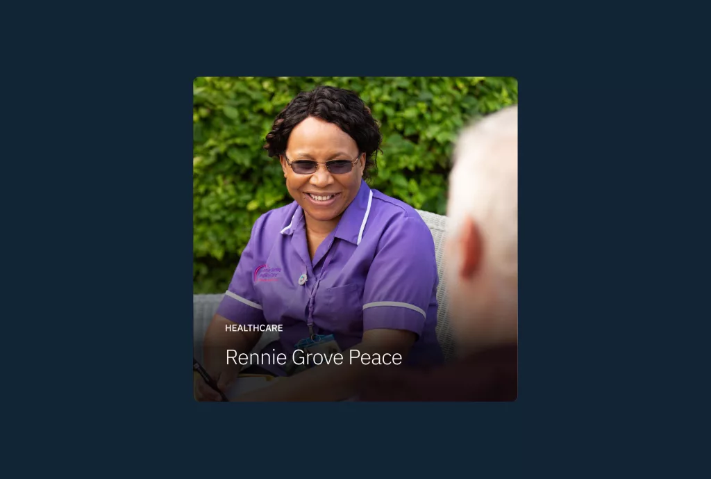 Smiling healthcare worker in a purple uniform and glasses talking with an elderly person outdoors, with overlay text Rennie Grove Peace