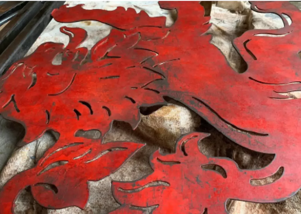 Weathered red laser-cut metal panels with stylised flame and feather motifs laid over a mottled brown hide.