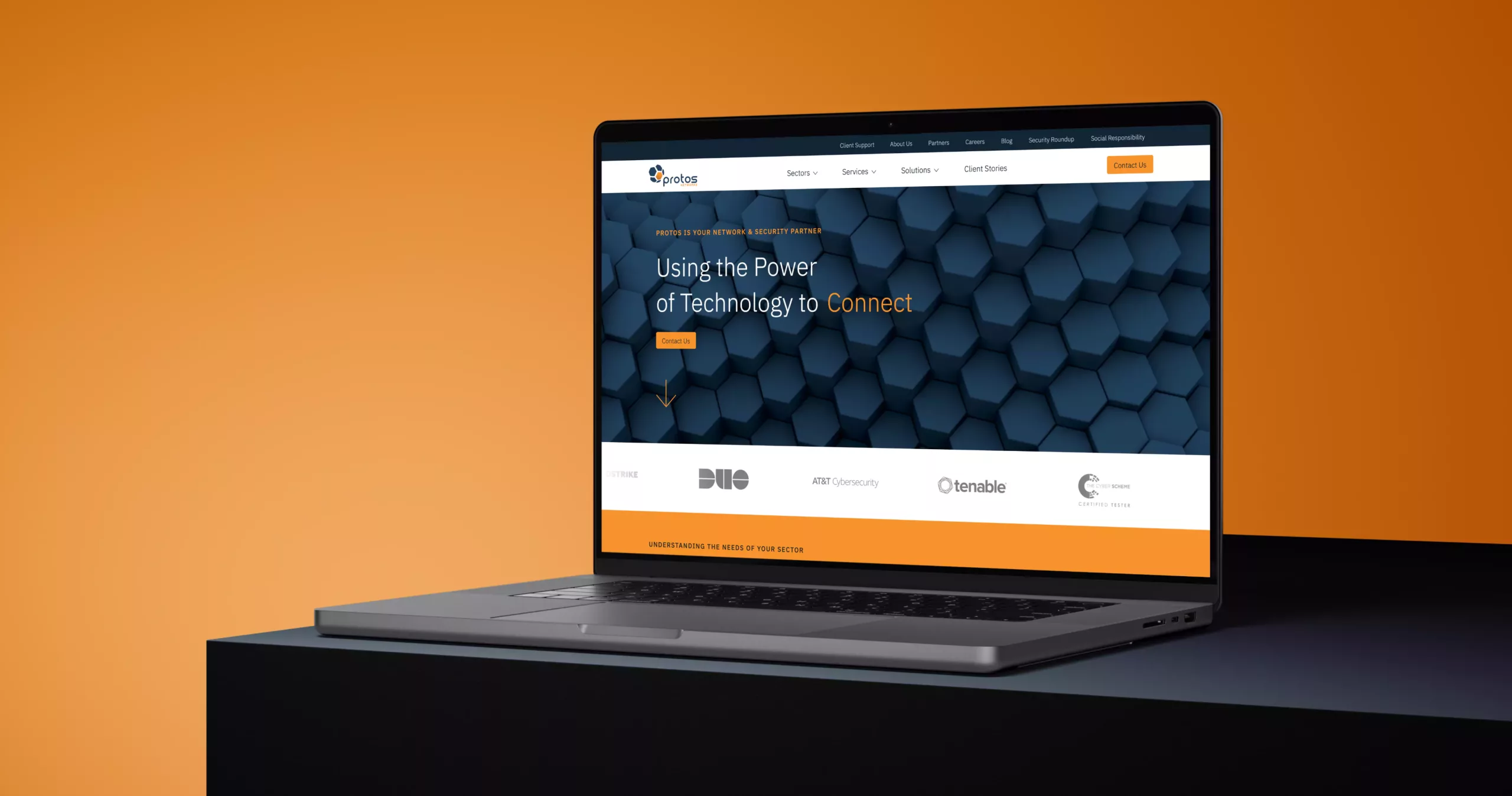 Laptop on a dark pedestal against an orange backdrop showing a tech site with blue hexagon background and orange accents.