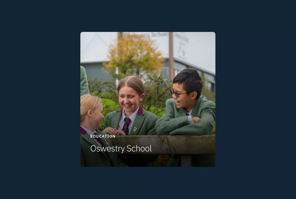 Three pupils in green blazers and ties laughing over a wooden fence, with Oswestry School text overlay.