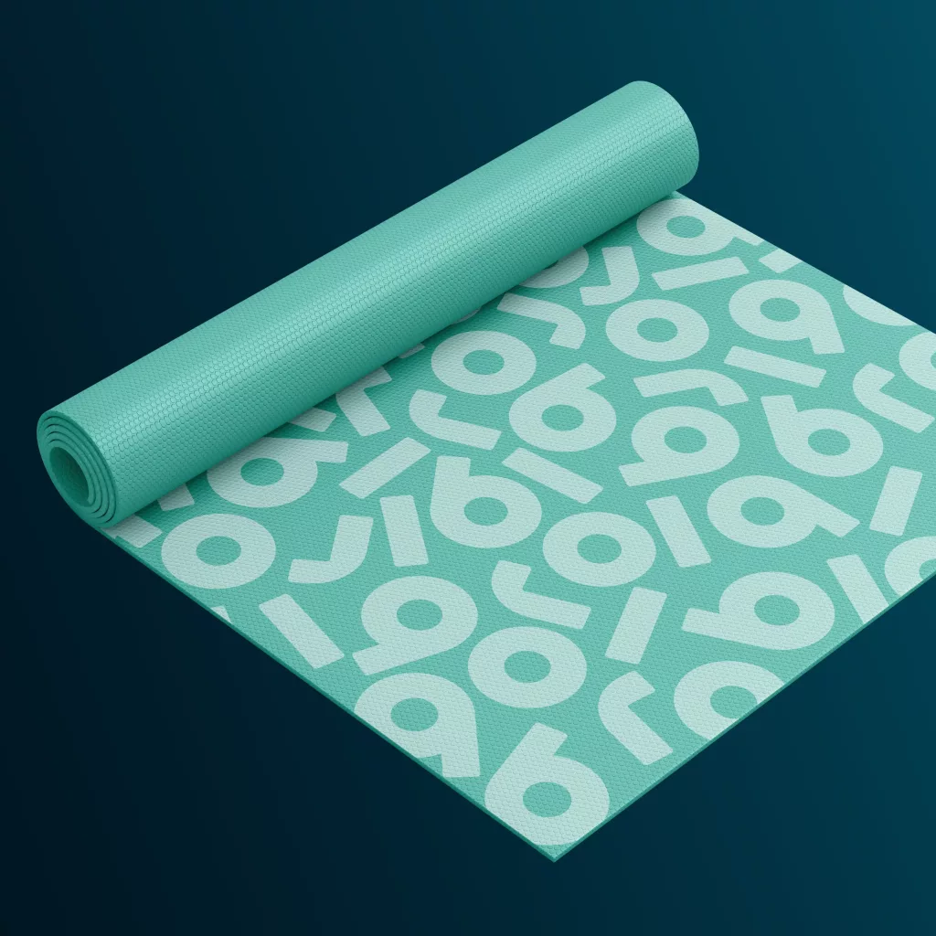 Rolled turquoise yoga mat with pale circular and angled geometric pattern and textured surface on dark teal background.