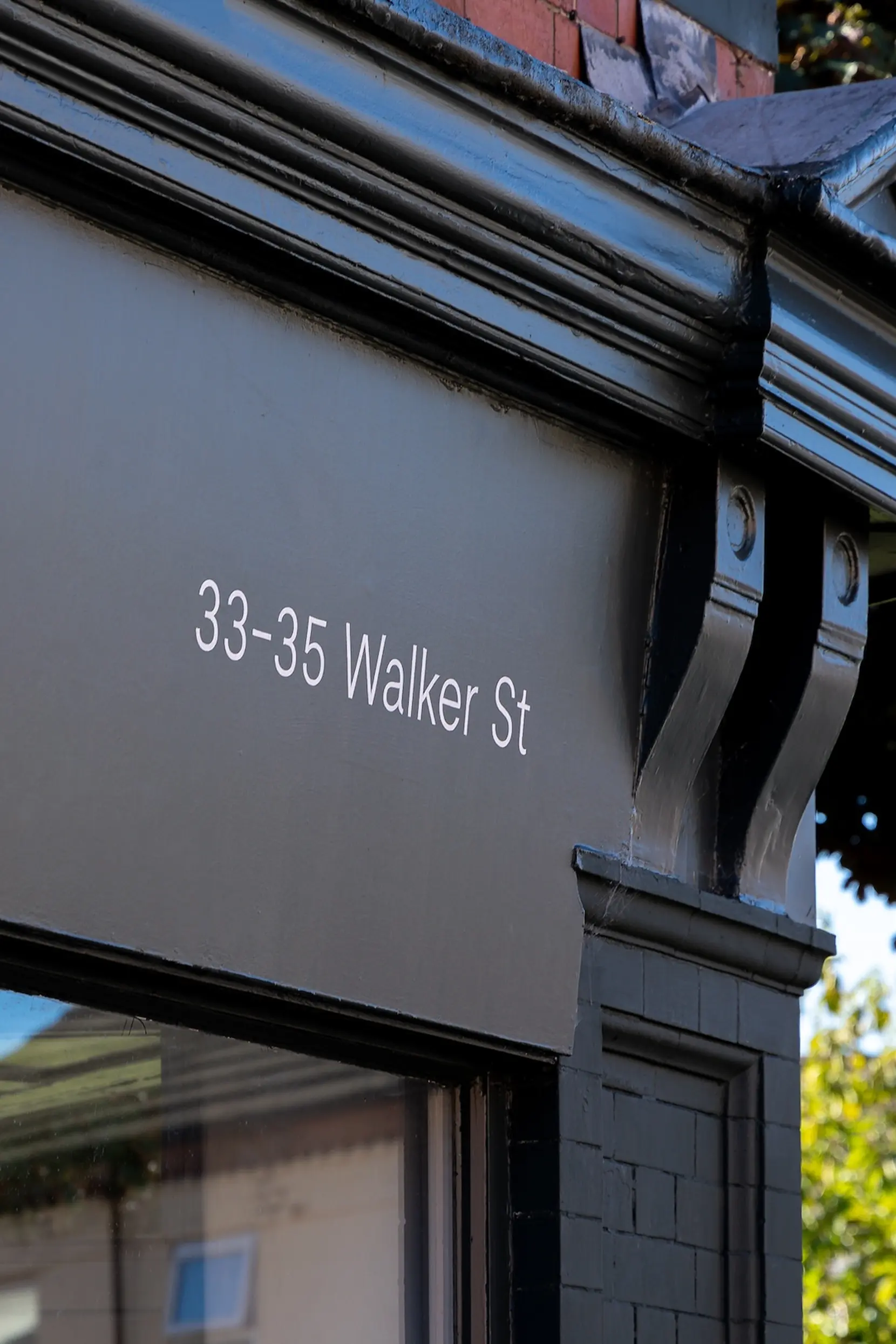 Black-painted building corner with decorative brackets and white address text 33-35 Walker St.